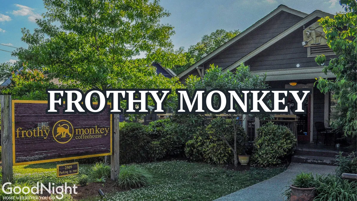 The entrance of Frothy Monkey, a popular local coffee shop, is shown with inviting steps, signage, and lush greenery. The space feels approachable and cozy, perfect for meeting friends or enjoying a quiet moment.