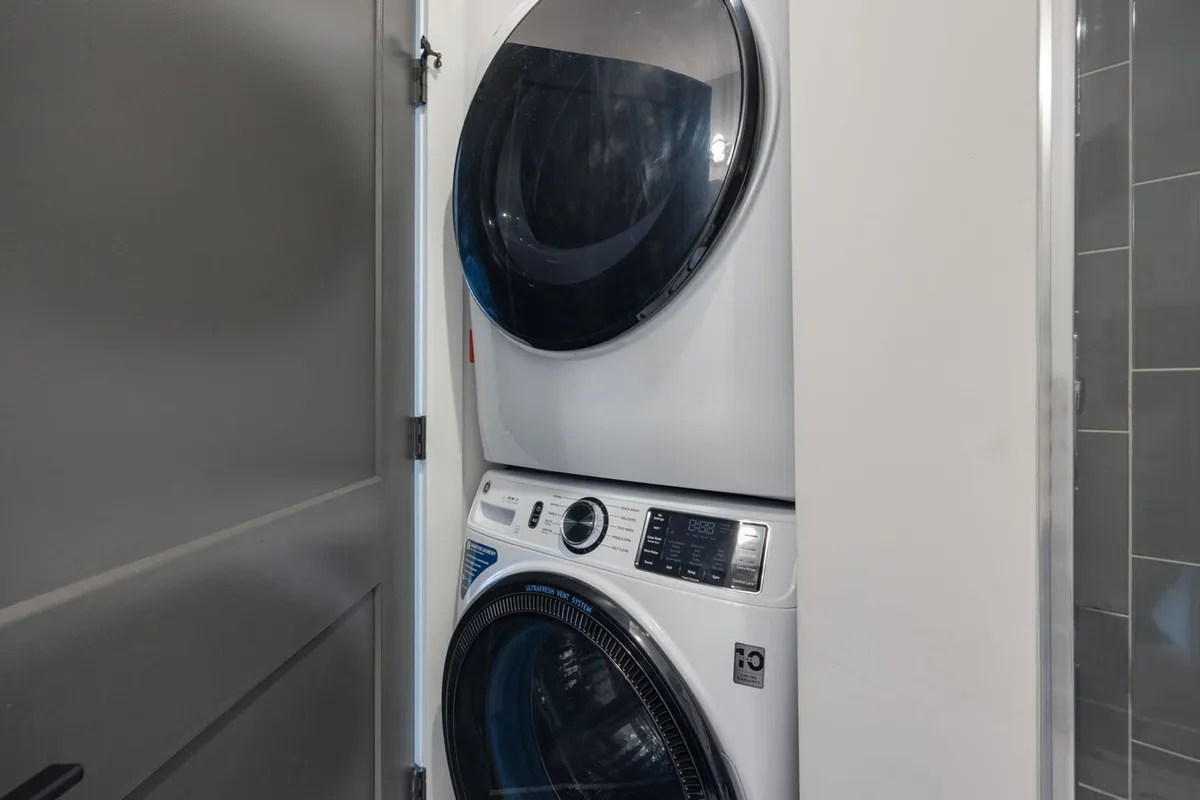 This image shows a stacked washer and dryer inside a dedicated laundry area, emphasizing practical conveniences for families. The space looks clean, modern, and accessible, supporting efficient family routines during travel.