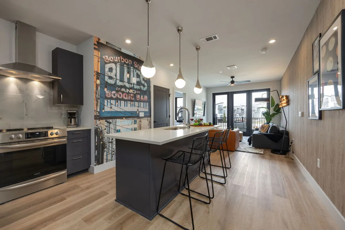 A stylish, contemporary kitchen and dining area featuring a spacious island countertop, sleek appliances, and an eye-catching vintage mural as a backdrop. The scene sets a warm, inviting atmosphere perfect for gatherings, with ample space for cooking, entertaining, and socializing.